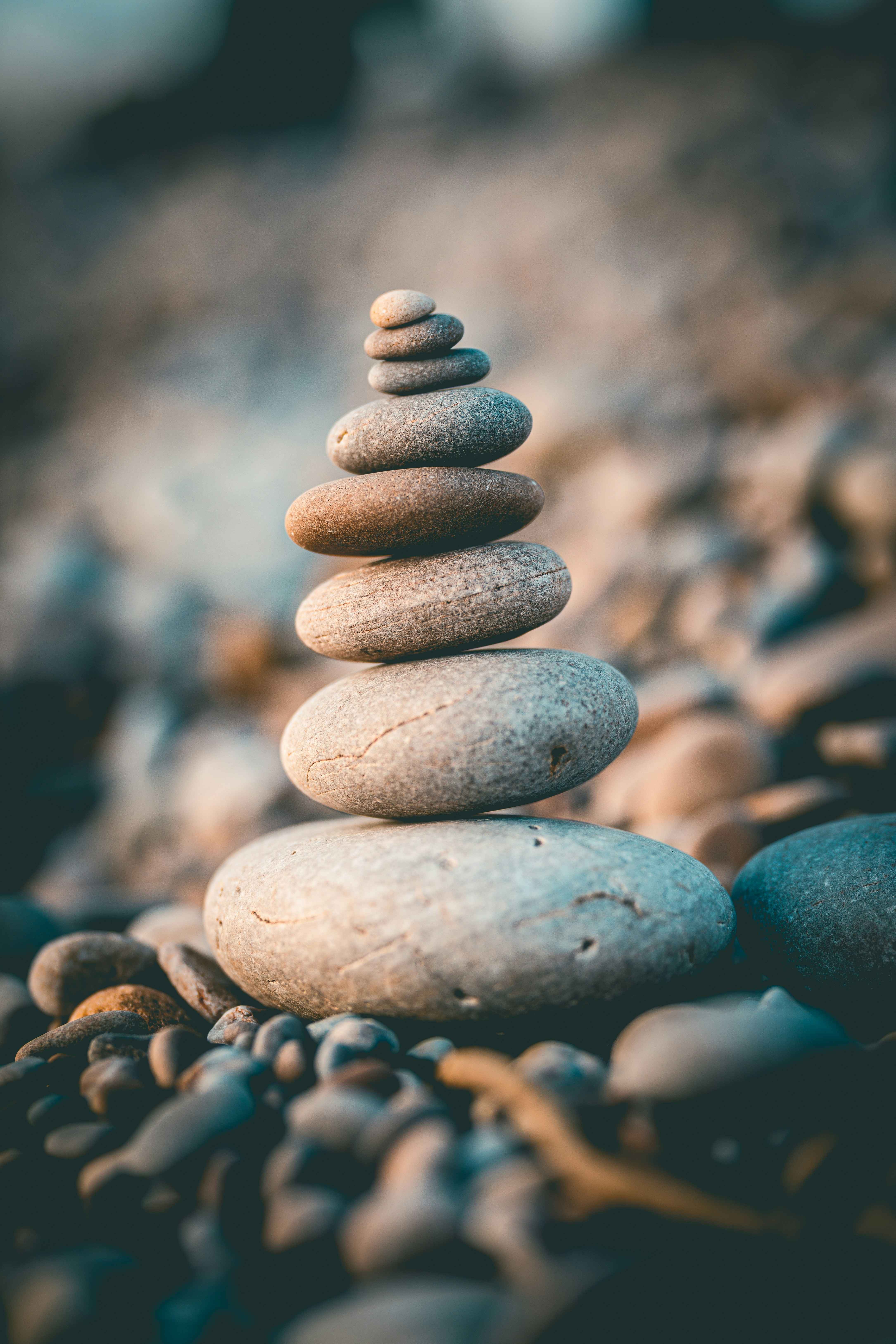 A serene image of a stack of smooth stones. Representing peace and tranquility. Photo by Rob Wicks on Unsplash.